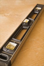 Close-up of black plastic and aluminum spirit level tool on plywood floor background, Studio