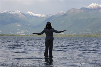 Woman Standing in a Flooding Alpine Lake Maggiore with Snowcapped Mountain in Locarno, ticino,