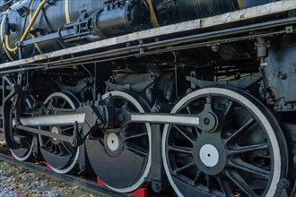 Side view of a black locomotive showing the complex mechanical details of wheels and parts, in