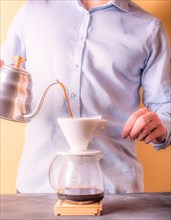 Person concentrating on manually brewing coffee with a pour-over filter setup, Vertical aspect