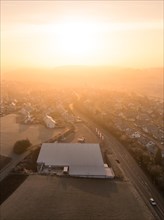 First rays of sunlight illuminate an industrial area seen from above, Gechingen, Black Forest,