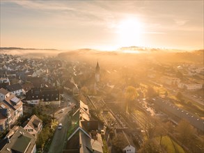 A church tower stands out as the town awakens in the sunrise light, Gechingen, Black Forest,