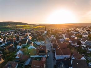 Village wrapped in the golden light of dusk with vast fields in the background, Calw, Black Forest,