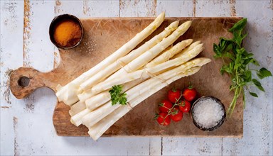 White asparagus on a cutting board with tomatoes and salt, carefully staged, fresh white asparagus,