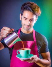 Man in a pink apron expertly pours coffee into a green cup with a look of satisfaction, Vertical