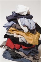 Close-up of pile of dirty clothes that includes blue jeans, underwear and t-shirts on white