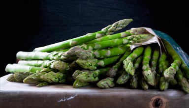 Green asparagus arranged on a rustic wooden board in front of a dark background, AI generated, AI