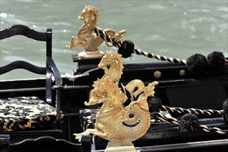 Close-up of a shiny golden dragon figure at the top of a Venetian gondola, Venice, Veneto, Italy,