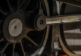 Close-up of a vintage train wheel showing intricate metalwork and interplay of shadow and light, in