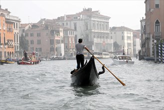 A gondolier navigates his gondola through the foggy canals of Venice, Venice, Veneto, Italy, Europe