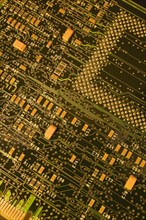 Close-up of dark green and golden yellow lighted electronic computer circuit board with lines and
