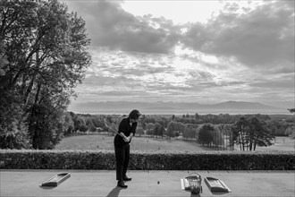 Woman on Driving Range with Panoramic View over Lake Geneva and Mountain in Switzerland. | MR:yes