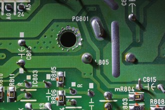 Close-up of green electronic computer circuit board with printed white numbers and letters and