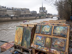 Kunstmarkt mit Gemaelden am Flussufer mit Blick auf Notre-Dame an einem bewoelkten Tag, Lifestyle