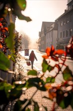 A person walking along a city street in the morning light, sunrise, Nagold, Black Forest, Germany,