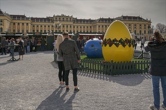 A couple looks at a large, decorative Easter egg in front of the magnificent Schoenbrunn Palace