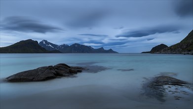 Seascape on the beach at Haukland. View of the mountains of Myrland on Flakstadoya. Dark sky,