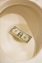 Top view and close-up of US one dollar bank note thrown down and floating in toilet bowl, Studio