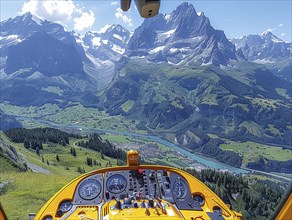 Blick aus dem Cockpit eines Hubschraubers auf gruene Taeler und Berge an einem sonnigen Tag,