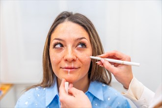 Plastic surgeon drawing lines in the face of a women marking where to injecting hyaluronic acid