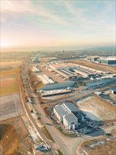 Sunlit aerial view of an industrial area with various warehouse buildings and streets, sunrise,