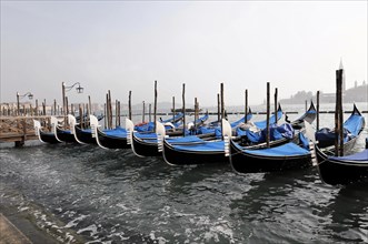 Several gondolas side by side in the misty waters of Venice, Venice, Veneto, Italy, Europe