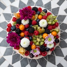 A decorative cake with fruit and flowers on a symmetrical tiled base, Germany, Europe