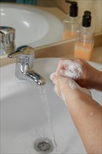 Closeup of a woman washing her hands with liquid soap suds in the bathroom sink. Hand hygiene from