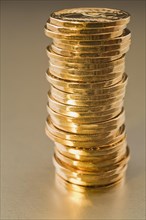 Close-up of stack of gold colored Canadian one dollar coins on silver background, Studio
