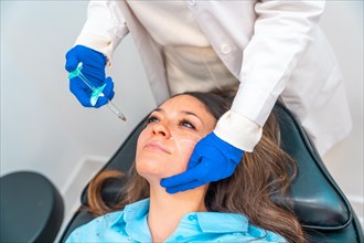 Elevated view of an unrecognizable female cosmetologist administering hyaluronic acid to the face