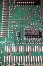 Close-up of green electronic computer circuit board with microchip, silver solder points and lines,