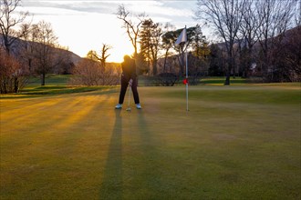 Female Golfer Concentration on the Putting Green on Golf Course in Sunset in Switzerland. | MR:yes