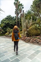 A woman enjoying and walking in a tropical botanical garden with many captus