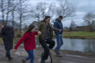 Family walk, a young woman with a unicycle, motion blur, Mecklenburg-.Vorpommern, Germany, Europe
