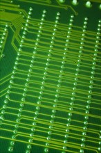 Close-up of fluorescent green lighted electronic computer circuit board with lines and silver