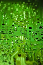 Close-up of green lighted electronic computer circuit board with silver solder points and lines,