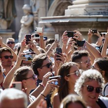 Many tourists stand close together and take selfies with their cell phones, photo quality Job ID: