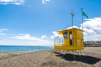 Yellow lifeguard tower in California with green flag