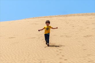 Tourist boy smiling in the dunes of Maspalomas, Gran Canaria, Canary Islands