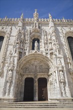 Jeronimos Monastery facade with arched front entrance door decorated with carved sculptures,