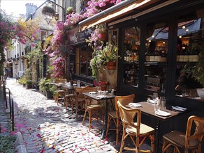 Gemuetliches Cafe mit Blumen dekoriert und leeren Tischen auf Kopfsteinpflaster, Lifestyle in