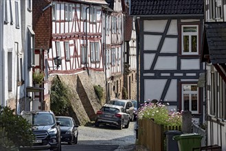 Old half-timbered houses on a narrow alley, parked cars, Untergasse, old town, Ortenberg,