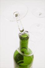 Close-up of upside down wine glass on top of consumed and empty red wine bottle, Studio