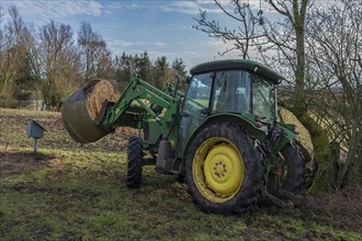 A tractor takes a bale of hay to the pasture, Mecklenburg-Western Pomerania, Germany, Europe