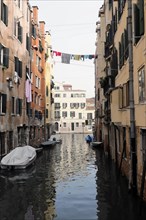 View of a Venetian canal with boats and washing lines between the houses, Venice, Veneto, Italy,