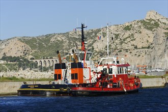 Red tugboat waiting in the harbour area next to a jetty, Marseille, Departement Bouches-du-Rhone,