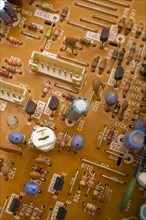 Close-up of orange electronic computer circuit board with capacitors and transistors, Studio