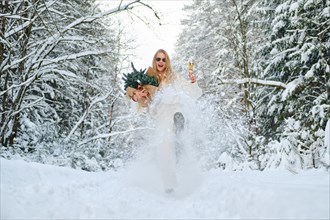 Low angle view of laughing woman kicking snow in winter forest