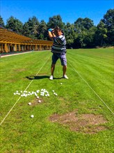 Man training Golf swing on driving range in a sunny day in Switzerland. | MR:yes Mats-CH-02-05-2023