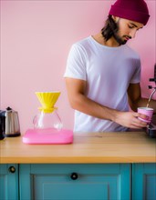 A focused man in a white tee using a vibrant pink coffee machine on a teal cabinet, Vertical aspect